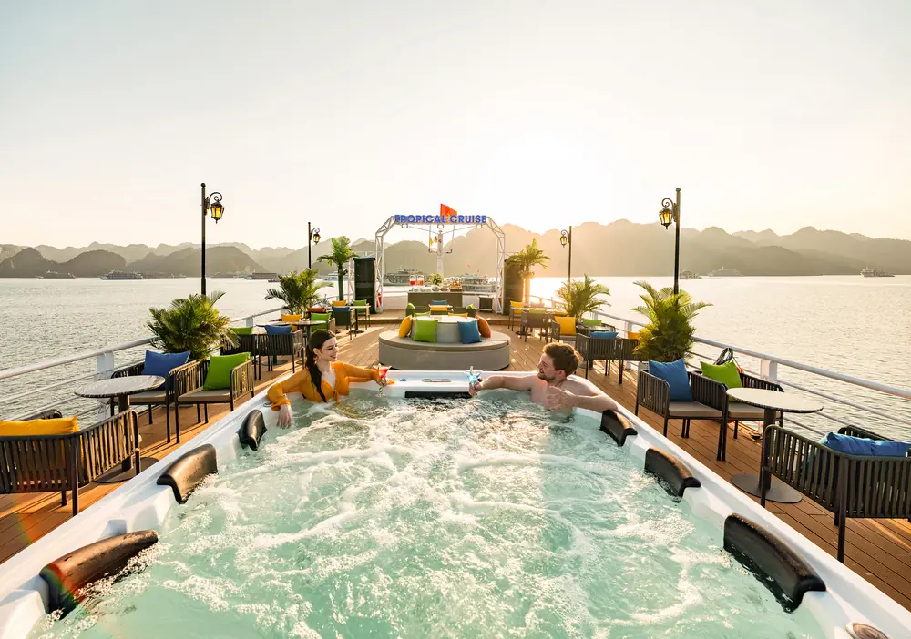 Guests relaxing in the rooftop Jacuzzi at sunset aboard the Tropical Cruise