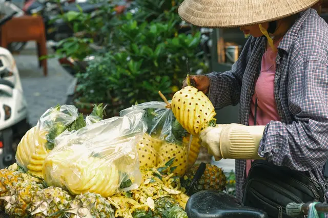 A vendor cutting a fresh pineapple