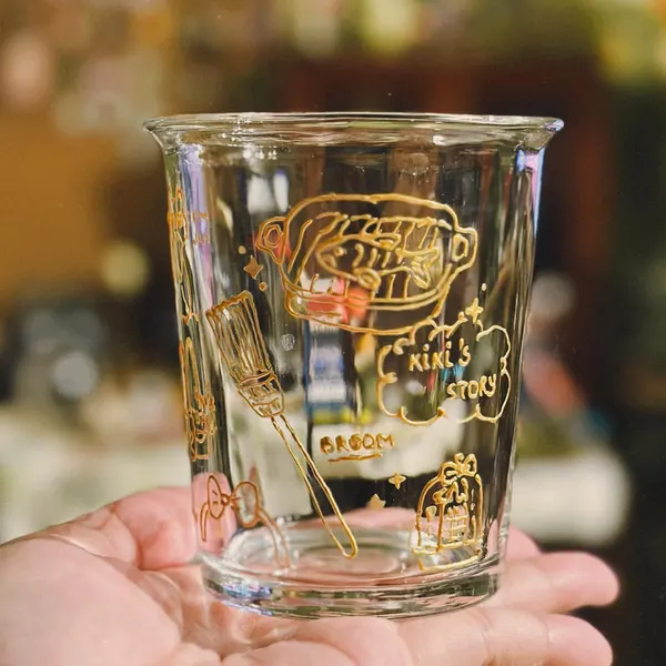 A finished hand-painted glass cup held in the palm of a hand