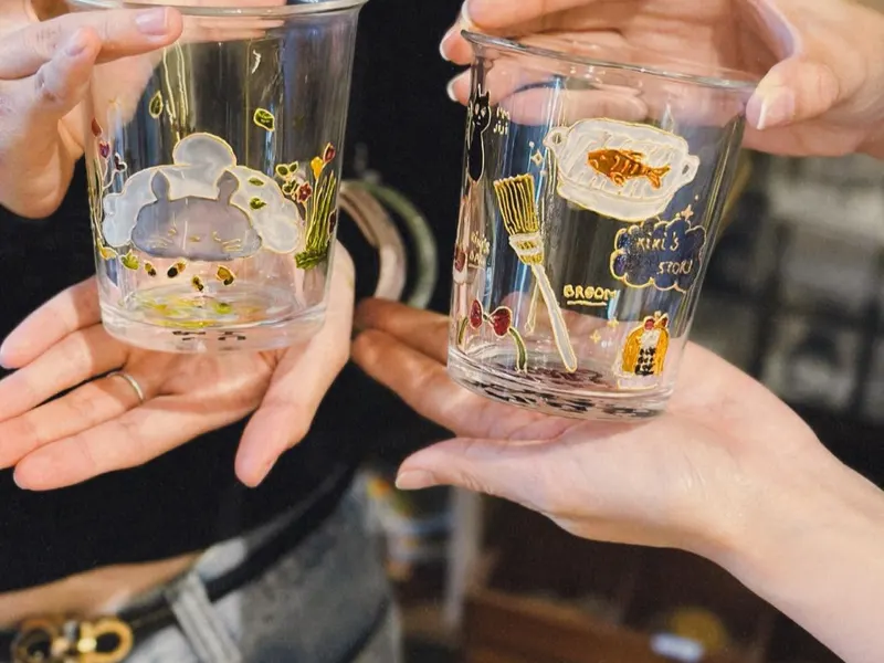 Two friends holding up the glass cups they painted