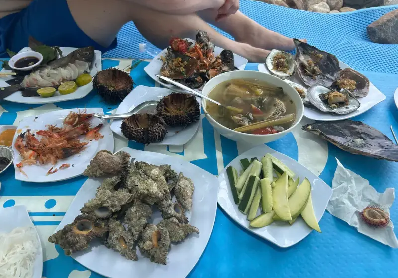 Seafood lunch spread out on the island: soup, shellfish and greens