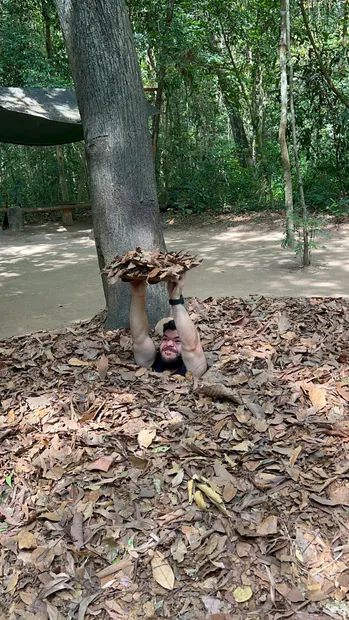Gast zeigt eine versteckte, getarnte Falltür in Củ Chi