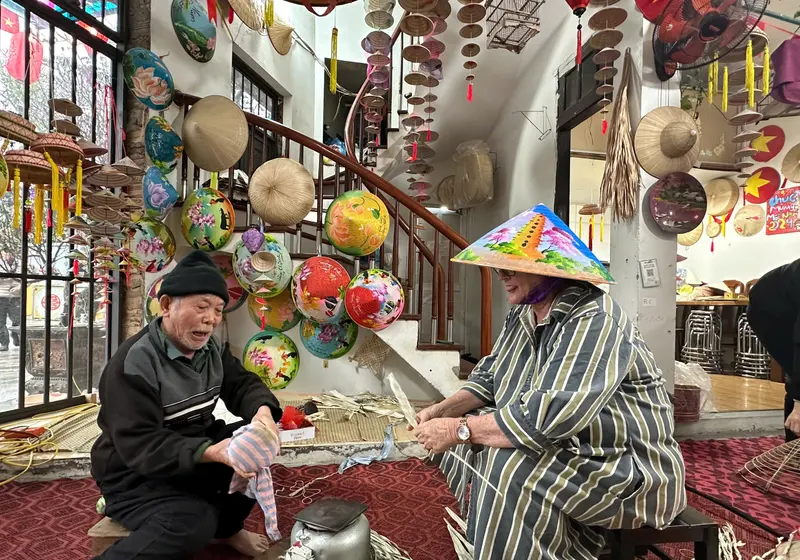 Two artisans stitching conical hats in the Chuong village workshop