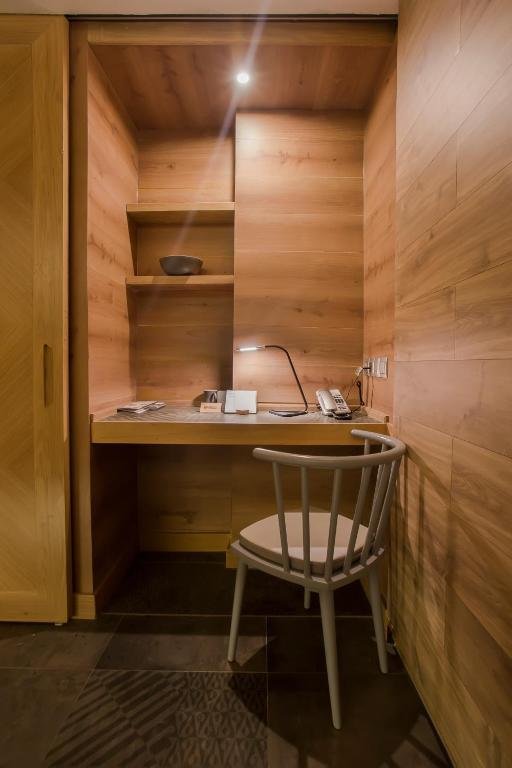 A timber-lined desk nook with shelves, a reading lamp, a telephone and a grey spindle-back chair beside the wardrobe