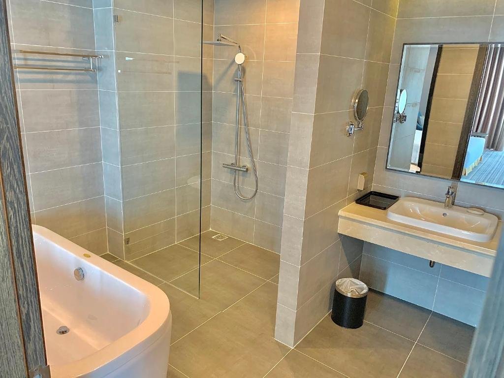 The walk-in shower behind a glass screen, the edge of the bathtub in front, and a basin with a magnifying mirror on the right
