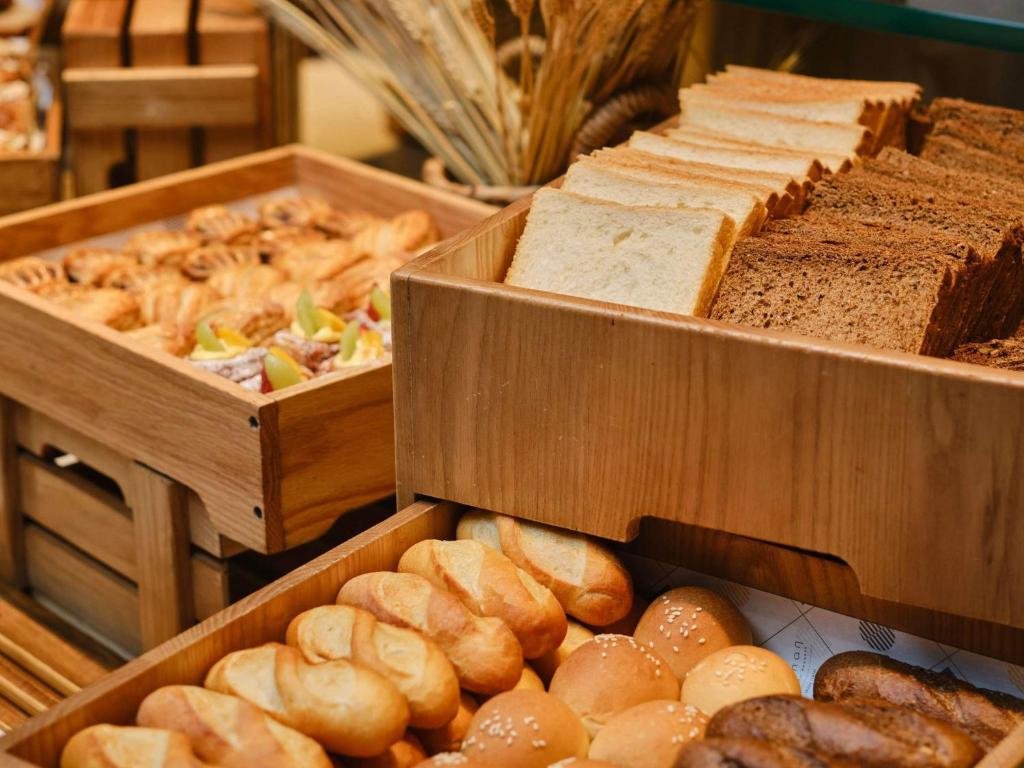 Wooden crates of sliced white and brown bread, bread rolls and fruit Danish pastries at the buffet