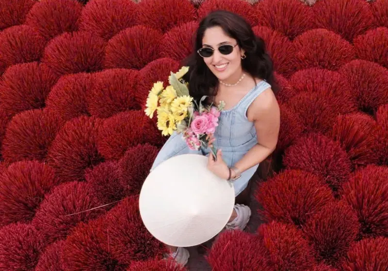 A visitor standing among fans of red incense sticks at Quang Phu Cau