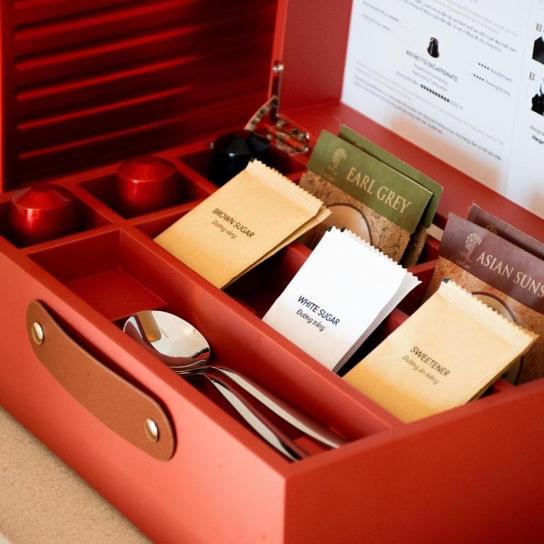 The in-room drinks box open on the desk: espresso capsules, Earl Grey and Asian Sunset teabags, and sachets of sugar and sweetener