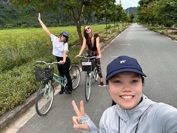Guests riding city bikes along a flat tree-lined road