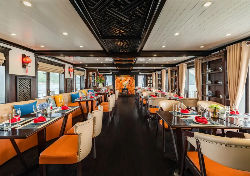 The restaurant aboard Cozy Grand: dark carved ceiling, red lanterns, orange and cream leather chairs at set tables