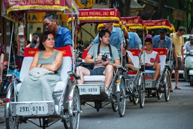 A line of cyclos carrying guests along a shaded street in Hanoi&rsquo;s Old Quarter