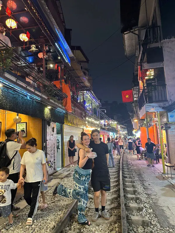 Cafes and travellers lining the narrow railway track of Hanoi train street at night