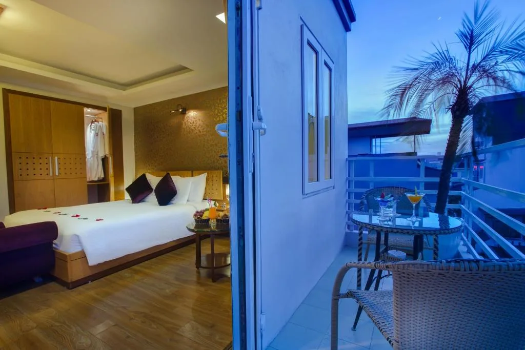 Room opening onto a private balcony set with wicker chairs, a glass table and a palm