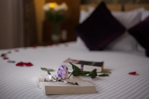 Turn-down detail: a book, reading glasses and a rose laid out on the bed