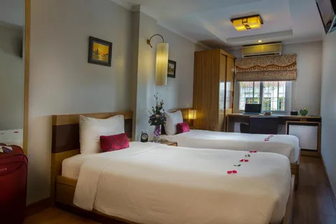 Superior Twin: two single beds with red cushions, a desk under the window and a wardrobe beyond