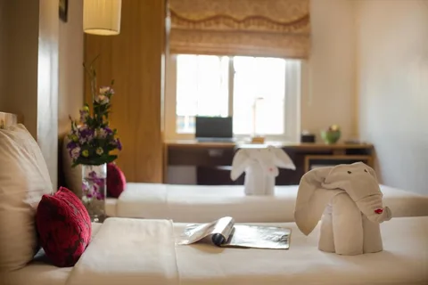 Superior Twin: a towel elephant and fresh flowers set out on the turned-down bed