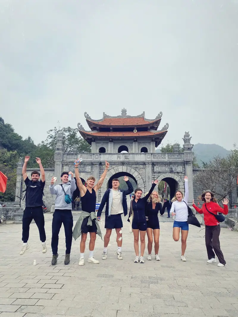 A happy group jumping in front of the stone east gate of the old Hoa Lu citadel