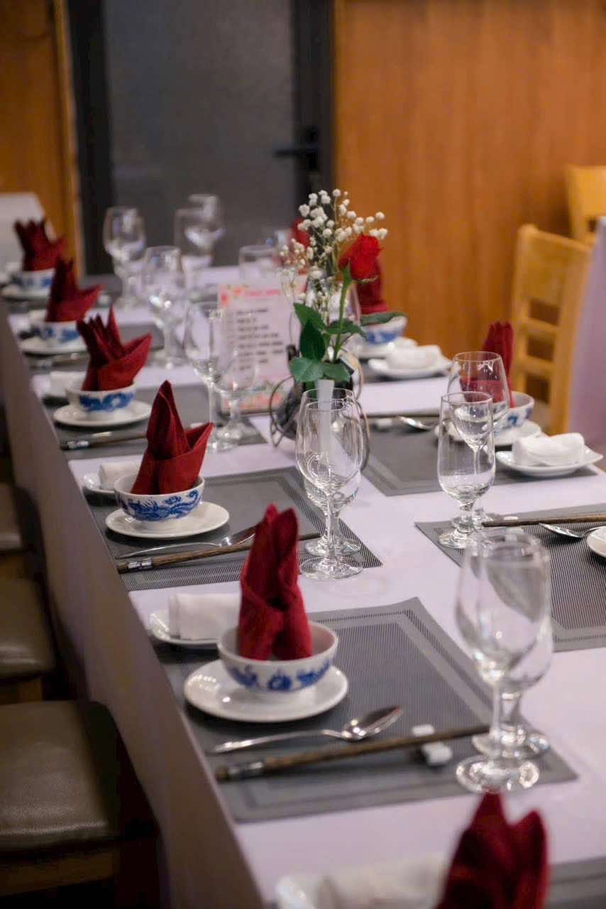The dinner table laid with red napkins, blue-and-white bowls and a single rose