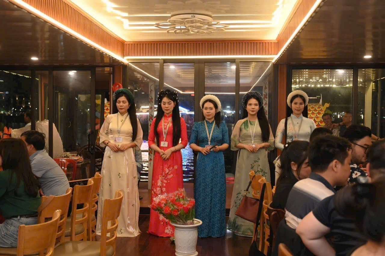 Five Ca Huế singers in áo dài standing to perform in the boat saloon