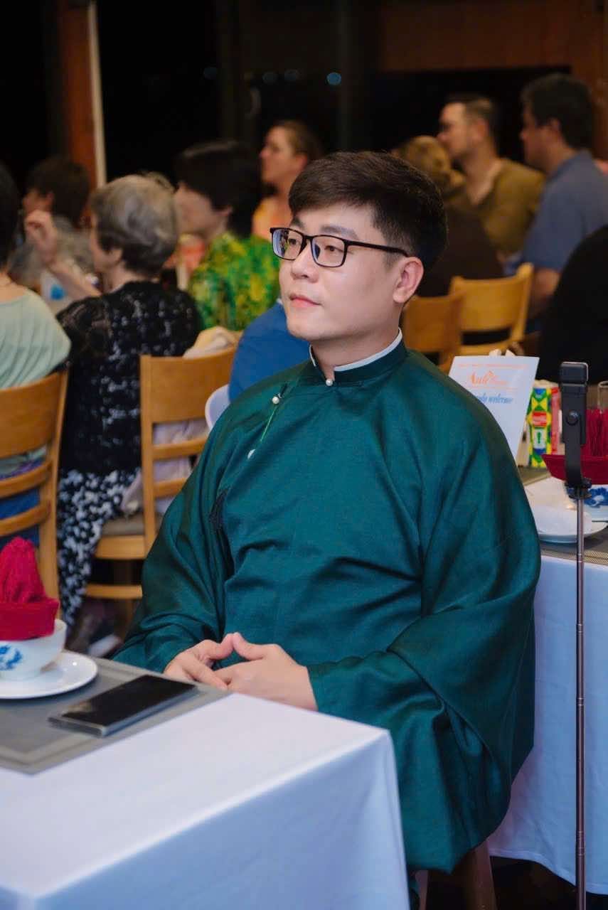 A guest in a green áo dài watching the performance