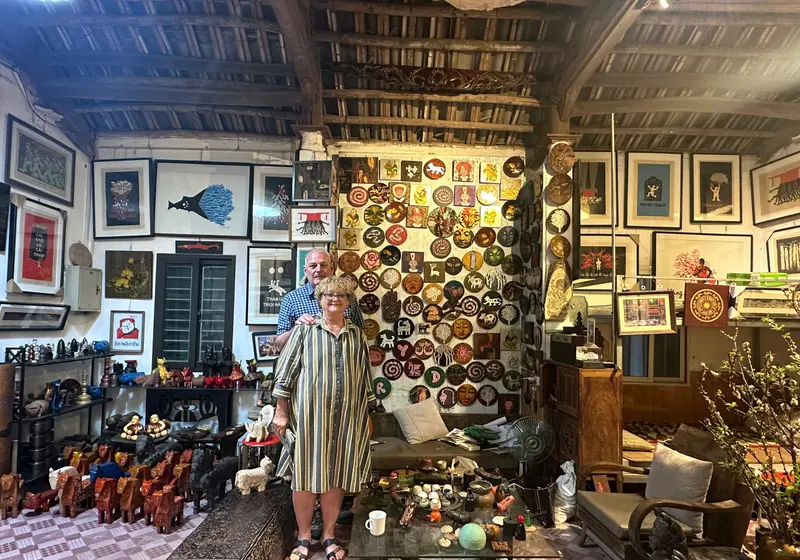 A guest in a Ha Thai lacquer artisan's house, walls covered with lacquered plates and paintings