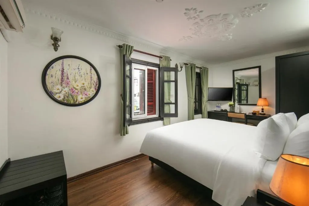 Room with a king bed, shuttered window and a framed botanical print