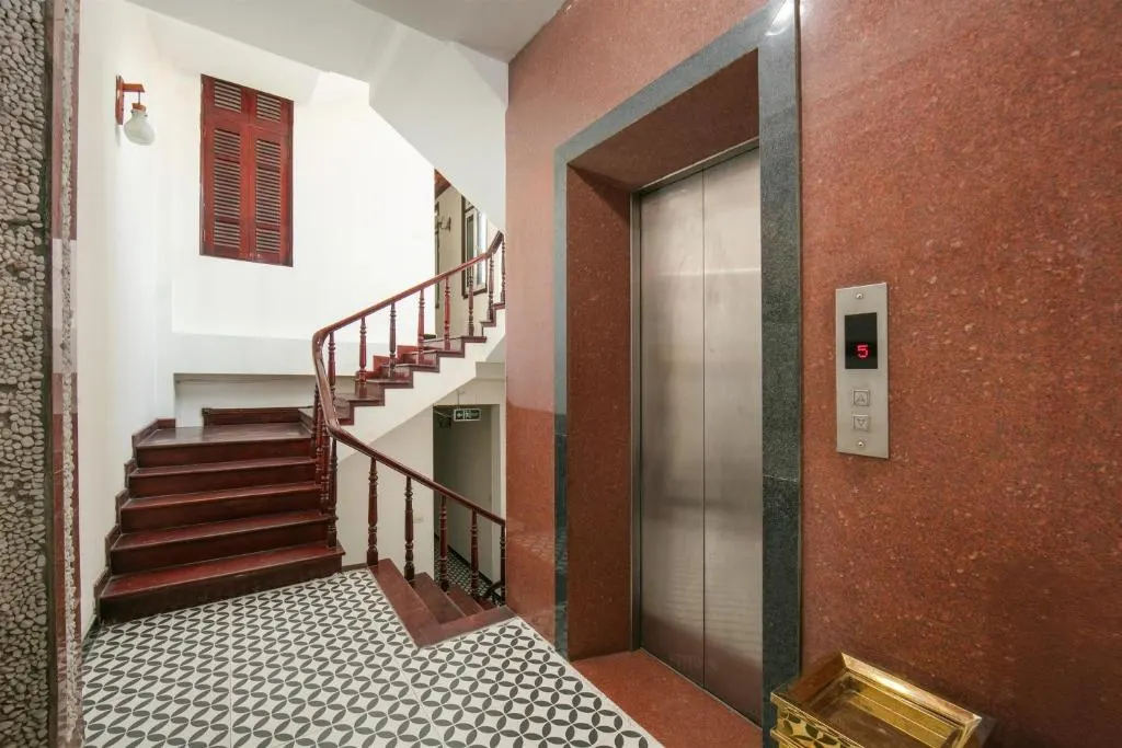 Stairwell and lift with a wooden banister and patterned tiles