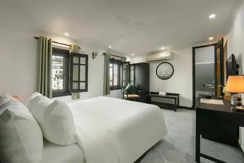 Deluxe Double: corner room with windows on two walls, a stone floor and a desk