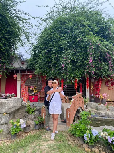 A flower garden at the park with a small red bridge, hanging lanterns and bougainvillea