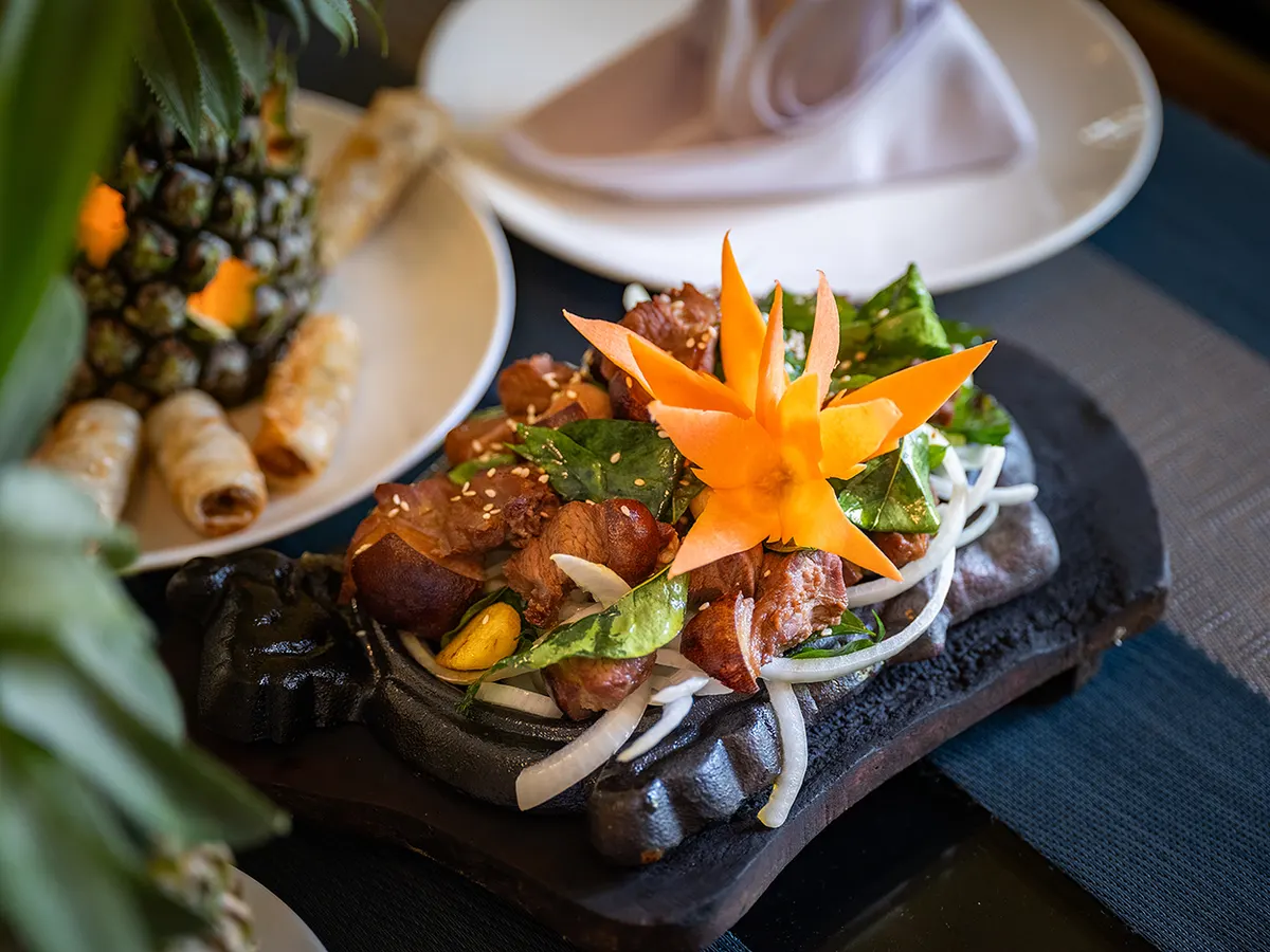 Grilled meat served on a hot stone with spring rolls